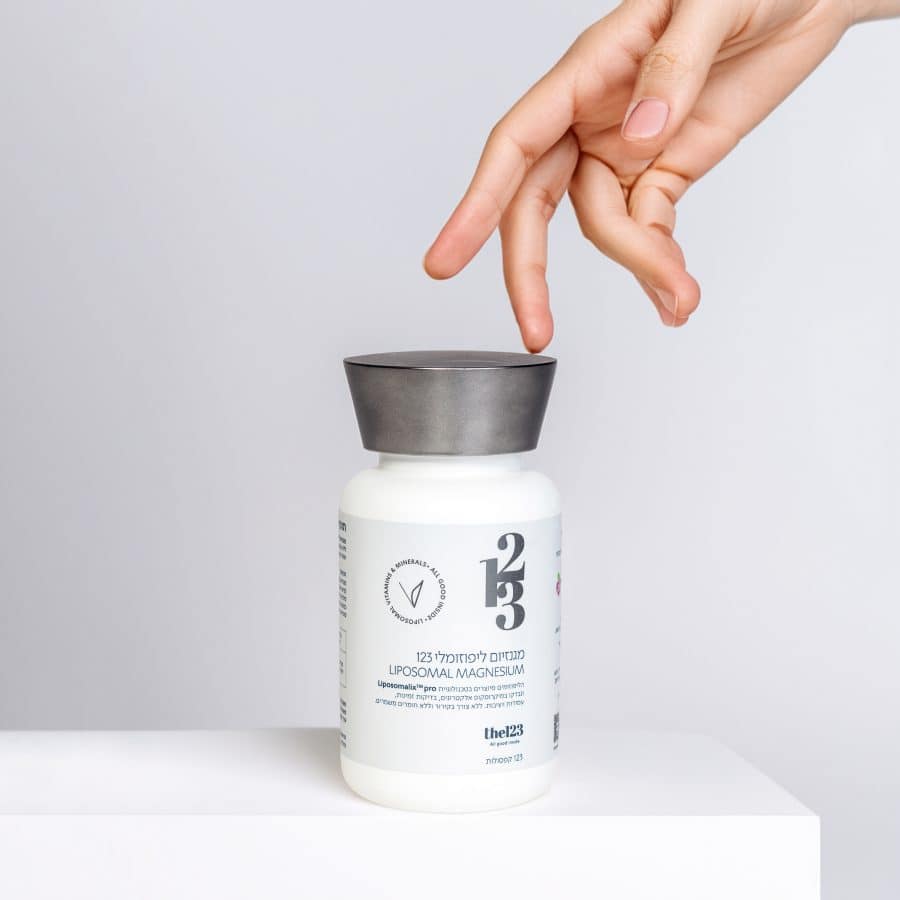 יד נשית נוגעת באלגנטיות בבקבוק של מגנזיום ליפוזומלי 123