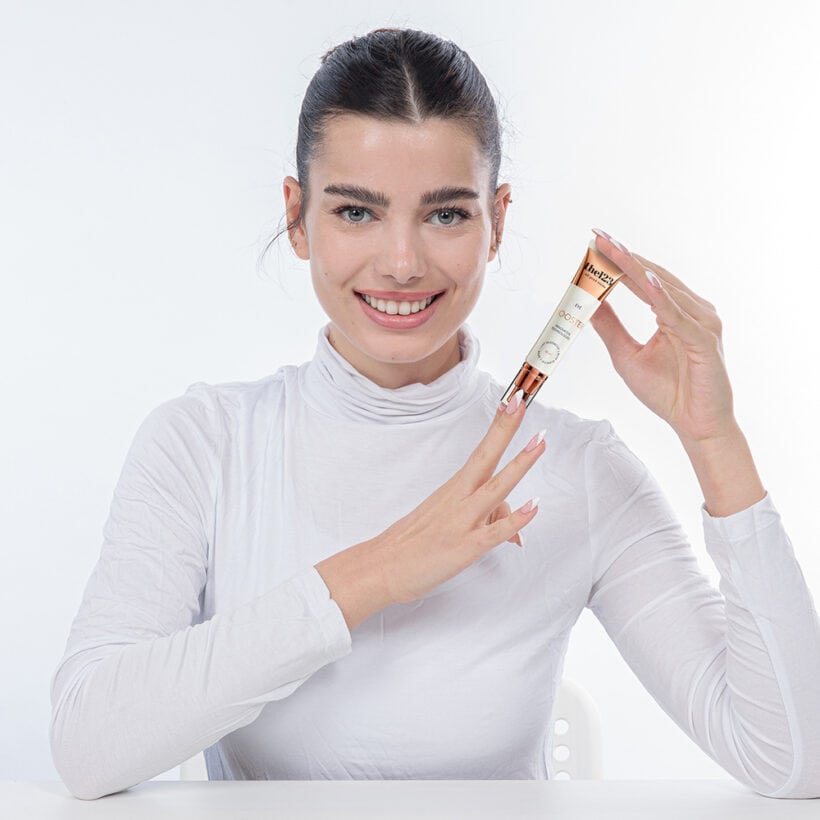 אישה צעירה נאה מחייכת למצלמה, בזמן שהיא מחזיקה בידה שפורפרת של