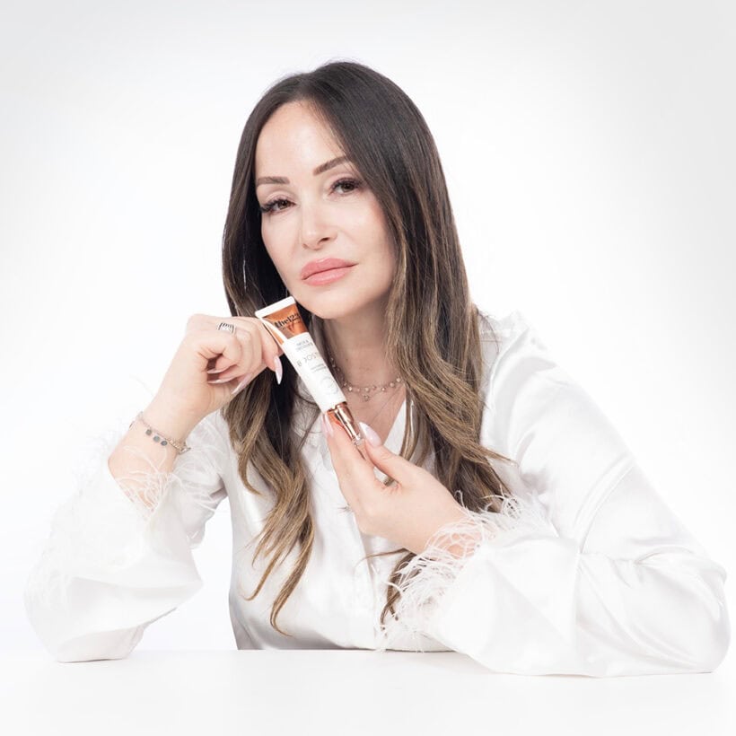 אישה נאה מסתכלת למצלמה בהבעת פנים המשדרת רוגע וביטחון, כאשר היא מחזיקה בידה שפורפרת של בוסטר צוואר ודקולטה 123