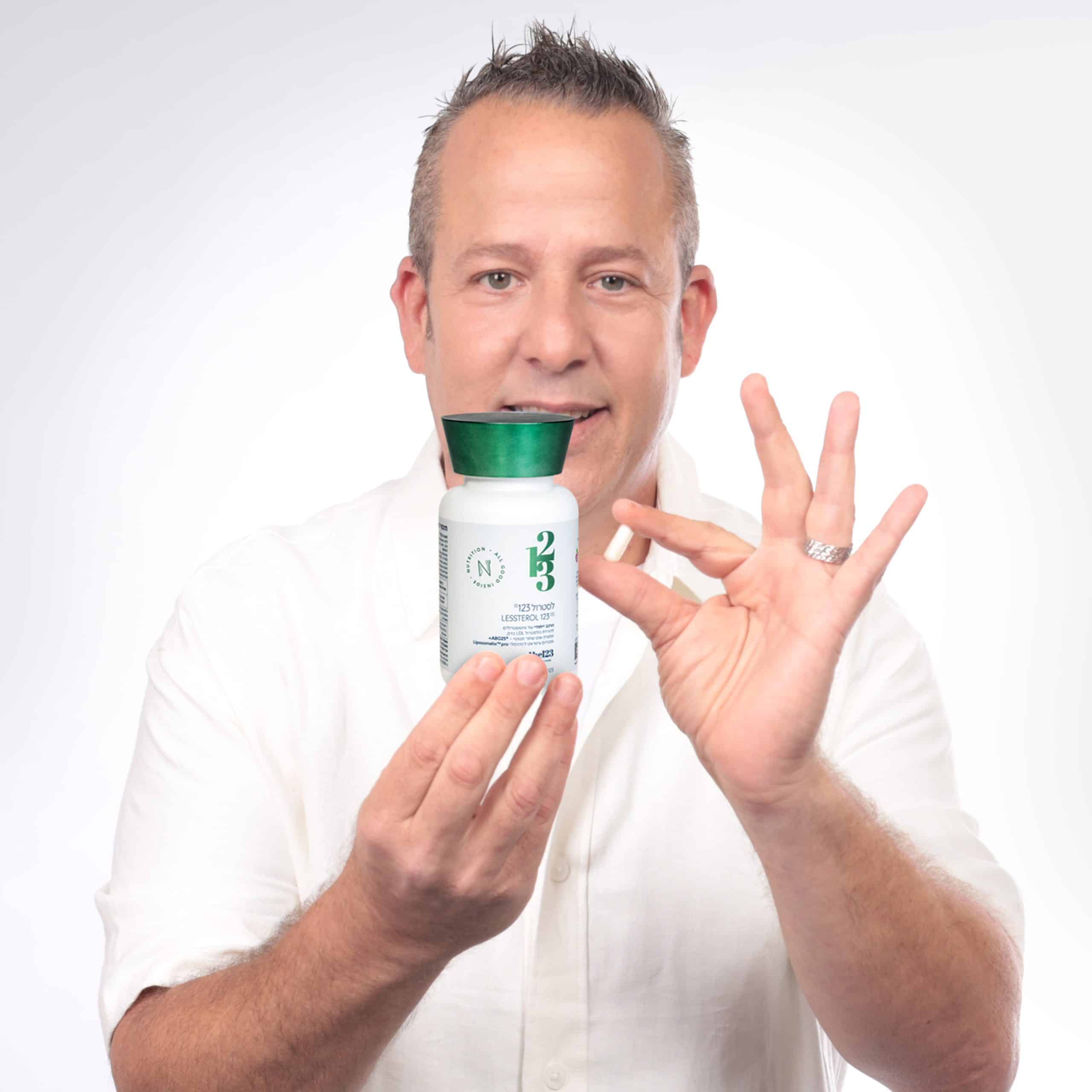 גבר נאה מחזיק בידו בקבוק של תוסף לסטרול 123