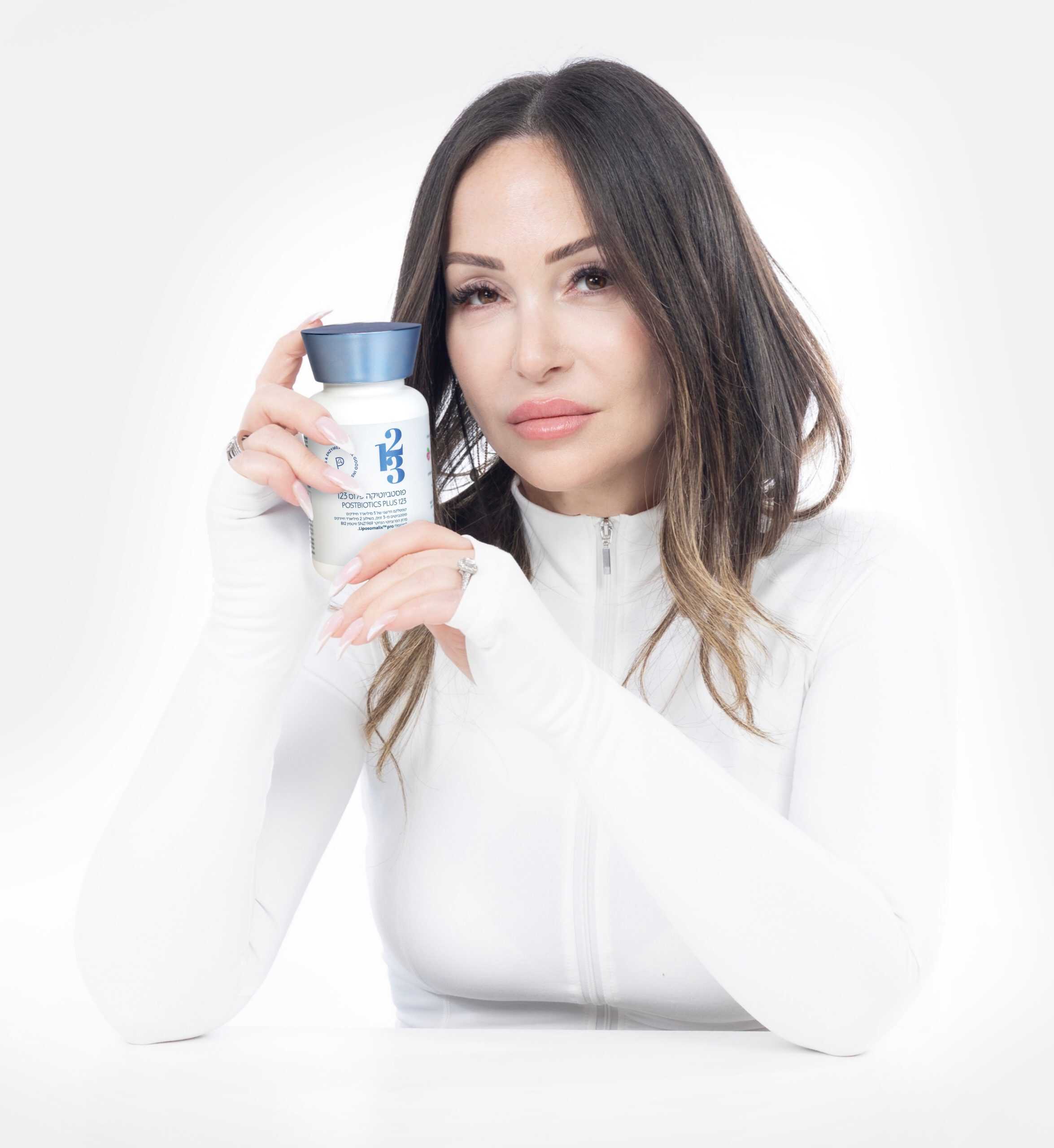 אישה נאה לבושה בלבן ומחזיקה בידיה פוסטביוטיקה פלוס מבית the123
